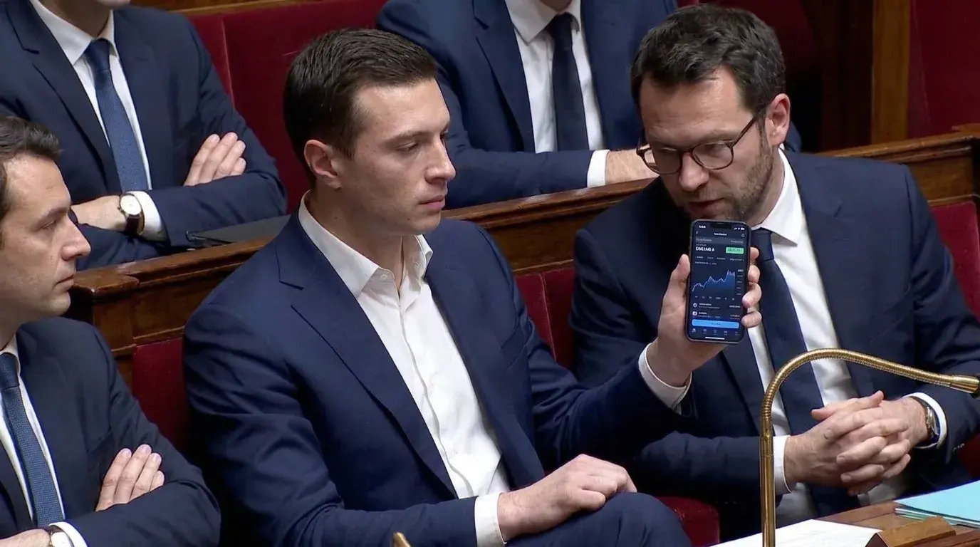 Un député assis à côté de Bardella montre son téléphone.